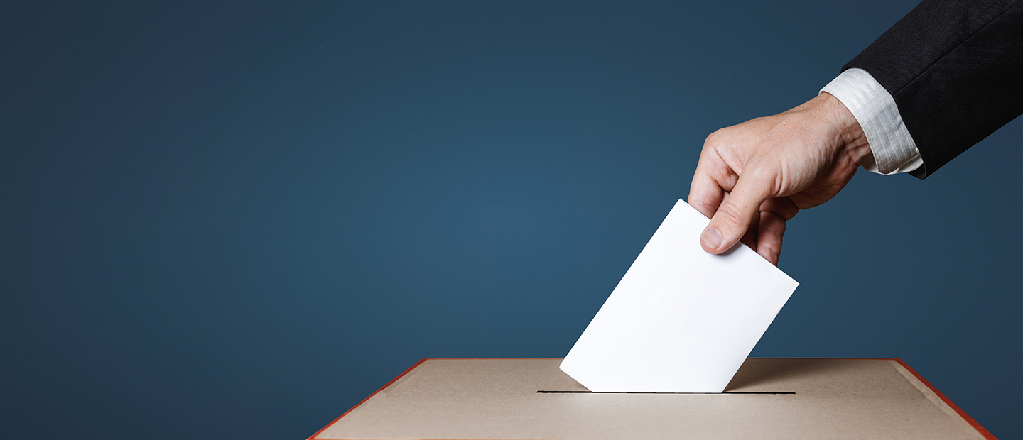 Closeup of hand putting ballot in a ballot box